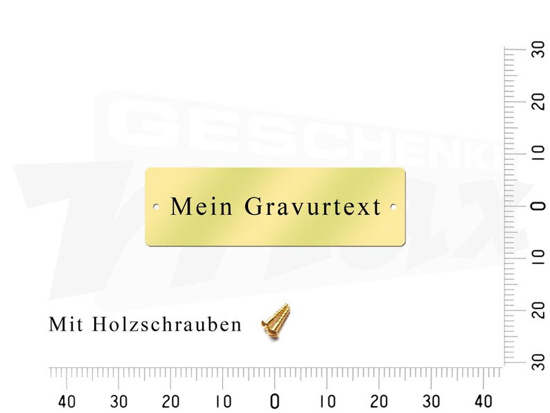 May include: A gold-colored metal plaque with the text "Mein Gravurtext" and two small holes for mounting. The plaque is shown on a white background with a ruler in the background.