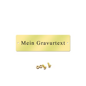 May include: A gold-colored metal plaque with rounded corners and two holes. The plaque has the text "Mein Gravurtext" engraved on it.