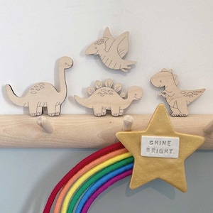 May include: Wooden dinosaur wall decor with a rainbow and a gold star that says "Shine Bright".