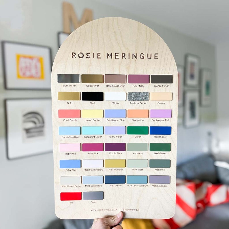 May include: A wooden chart with the title "Rosie Meringue" and a grid of 48 color swatches. The swatches are labeled with names like "Silver Mirror", "Gold", "Black", "White", "Coral Candy", "Lemon Bonbon", "Candyfloss Blue", "Spearmint Green", "Bubblegum Blue", "Orange Fuz", "Bubblegum Pink", "Parma Violet", "Green", "French Blue", "Baby Pink", "Rose Pink", "Purple Plum", "Avocado", "Leaf Green", "Baby Blue", "Matt Marshmallow", "Matt Mustard", "Matt Sage", "Matt Pine", "Matt Desert Beige", "Matt Dusky Blue", "Matt Denim", "Matt Duck Egg Blue", "Matt Lavender", "Red", "Silver".