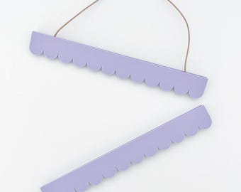 May include: A set of two light purple wooden poster hangers featuring a scalloped bottom edge. The top hanger includes a thin, flexible brown cord attached to both ends for hanging, while the bottom hanger is a separate matching piece.
