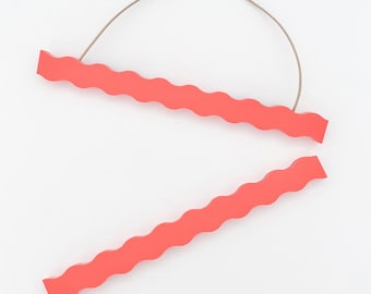 May include: Two coral-colored wooden poster hangers with a wavy edge design. The top hanger has a thin, brown string attached for hanging. The hangers are displayed against a white background.