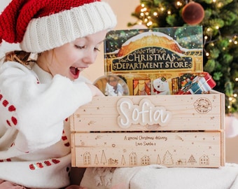 May include: A wooden crate with the name "Sofia" on it, filled with Christmas-themed items. The crate has a festive design with stars, houses, and trees. The text "A special Christmas delivery Love Santa x" is also visible.