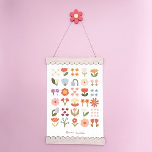 May include: A white print with a variety of colorful flowers in a simple, modern style. The print is framed in a light wood frame with a scalloped edge. The print says "Flower Garden" at the bottom.