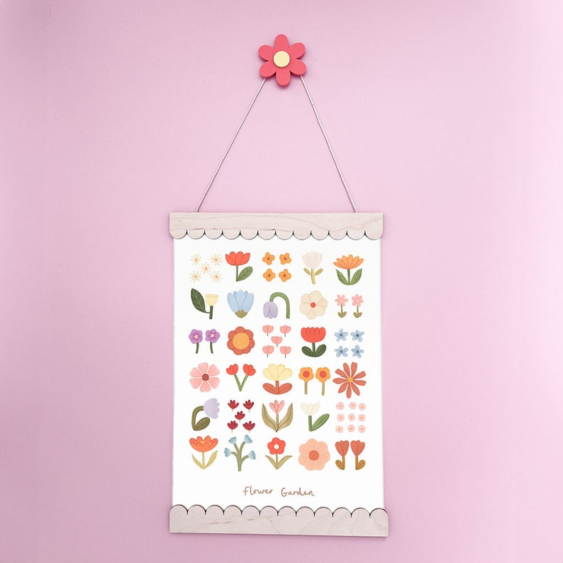 May include: A white print with a variety of colorful flowers in a simple, modern style. The print is framed in a light wood frame with a scalloped edge. The print says "Flower Garden" at the bottom.