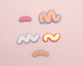 May include: Five colorful, abstract shapes made of paper, including a wavy line, a squiggle, a curved line, and two squiggles. The shapes are on a pink background.