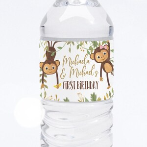 May include: A clear plastic water bottle with a white label featuring two cartoon monkeys and the text "Michaela & Michael's First Birthday".