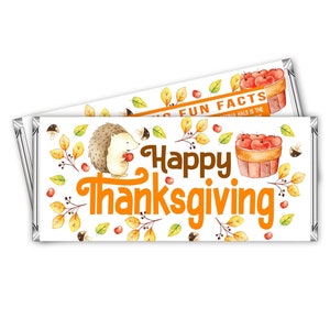 Op de afbeelding: Een witte chocolade reep verpakking met een feestelijk Thanksgiving ontwerp. De verpakking toont een egel die een appel vasthoudt, herfstbladeren en de tekst "Prettige Thanksgiving".
