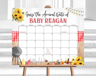 Op de afbeelding: Een wit, afdrukbaar babyshower-spelbord met een houten achtergrond. Het bord zegt "Raad de aankomstdatum van Baby Reagan" en heeft een kalender met de data september en oktober. De kalender is versierd met zonnebloemen, een grill en andere barbecue-thema-artikelen.