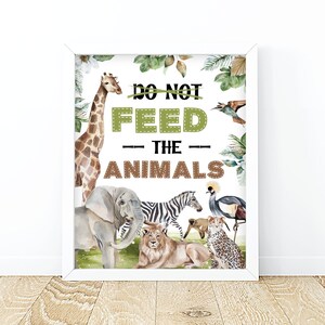 May include: A white framed print with a watercolor illustration of various jungle animals, including a giraffe, elephant, zebra, lion, cheetah, and a bird. The print has the text "Do Not Feed The Animals" in brown and green letters.