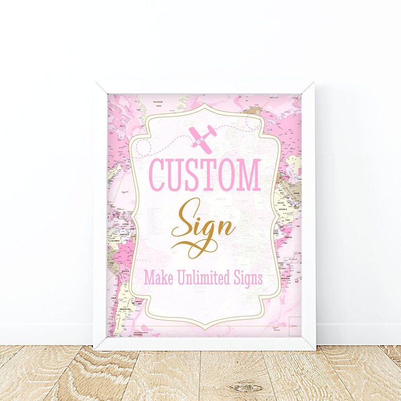 May include: A white framed sign with a pink and white world map background. The sign has a pink banner with a small pink airplane and the text "CUSTOM Sign Make Unlimited Signs" in gold lettering.