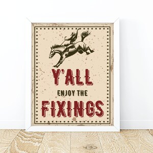 May include: A vintage-style poster featuring a cowboy riding a bucking horse. The poster has a distressed background and the text "Y'all Enjoy The Fixings" in red.