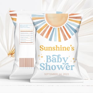 May include: A white chip bag with a watercolor sun design in shades of orange, yellow, and blue. The text "Sunshine's Baby Shower" is printed in blue and yellow with gold stars. The date "September 24, 2022" is printed below the text.