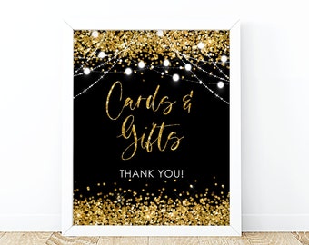 May include: A black and gold sign with the text "Cards & Gifts" and "Thank You!" surrounded by gold glitter and white string lights.