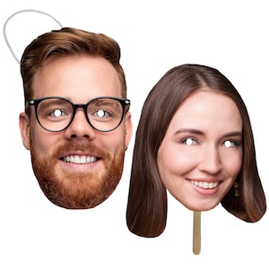 May include: Two cardboard face masks, one with a man's face wearing glasses and a beard, and the other with a woman's face. Both masks have white circles for eyes.