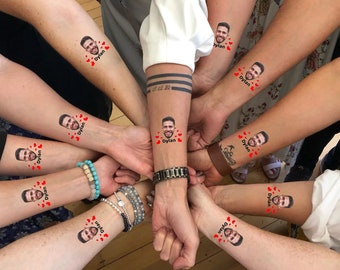 May include: A group of people with temporary tattoos on their arms. The tattoos feature a man's face with the name "Dylan" written below. The tattoos are surrounded by red hearts.