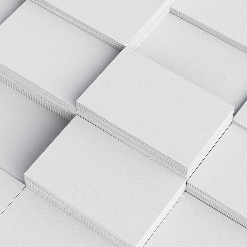 Neatly stacked piles of blank white business cards arranged in a grid pattern, displaying a clean and uniform appearance with a textured finish on a white surface.