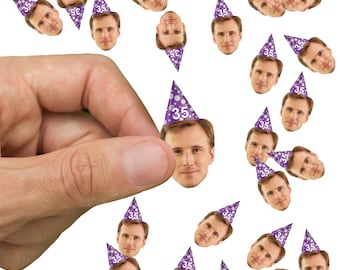 May include: Purple and white party hats with a number 35 printed on them. The hats are scattered on a white background. A hand is reaching towards the hats.