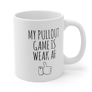 May include: White ceramic coffee mug with black text that reads "My pullout game is weak af" and a thumbs up icon.