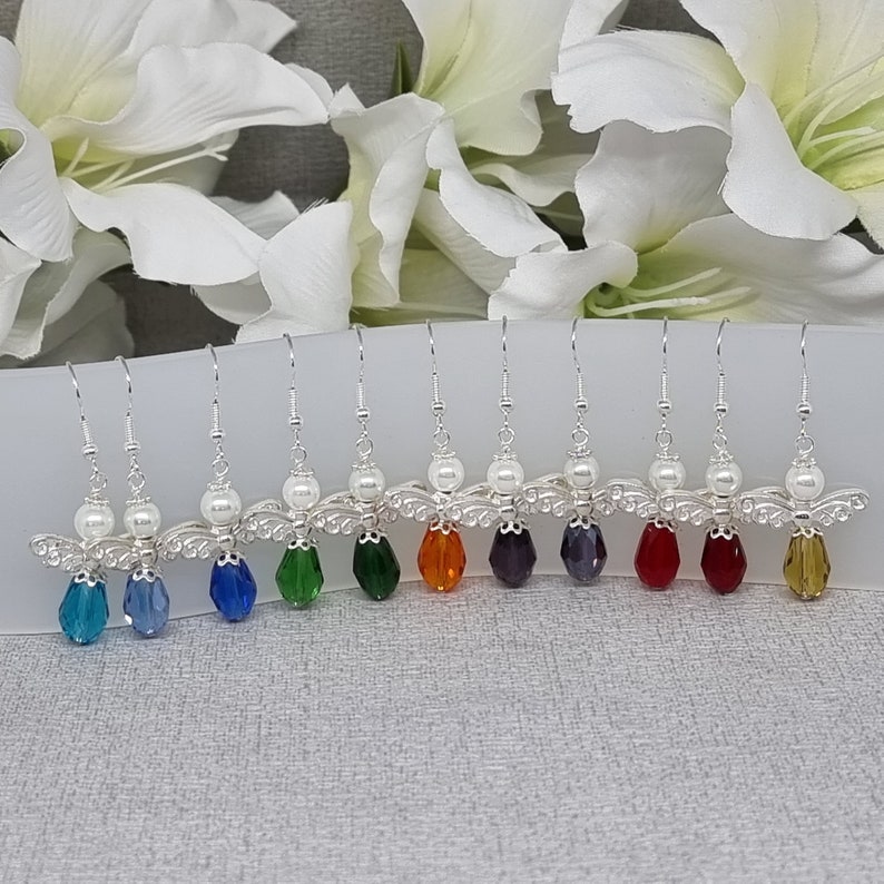 May include: A set of eight silver angel wing earrings with a pearl bead and a crystal drop. The crystals are in a rainbow of colours: blue, teal, green, orange, purple, red, and yellow.