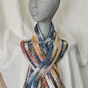 May include: A striped crocheted scarf in shades of blue, yellow, orange, and white. The scarf is displayed on a mannequin.