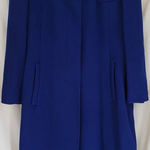 May include: A long, blue coat with a mandarin collar and a single button fastening. The coat has a label that reads "JGHOOK".