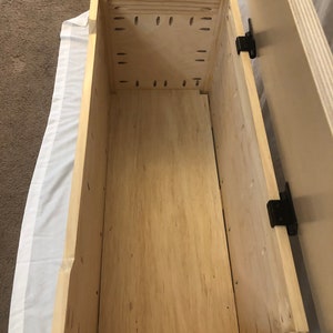 May include: The inside of a wooden storage box with a light wood finish. The box has a hinged lid and is empty.
