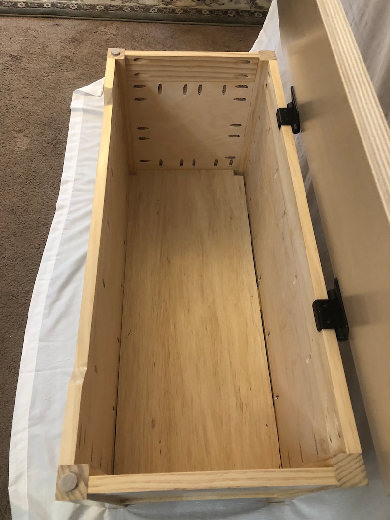 May include: The inside of a wooden storage box with a light wood finish. The box has a hinged lid and is empty.