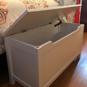 May include: White wooden storage chest with a hinged lid. The lid is open and the chest is empty.