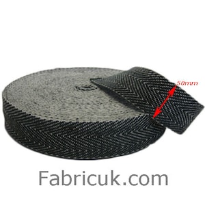 May include: A roll of black and white herringbone webbing, 50mm wide. The webbing is made of a woven fabric and has a textured surface.