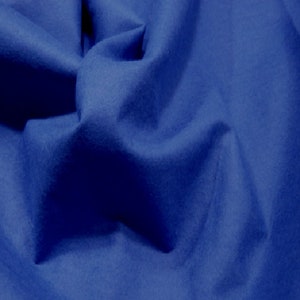 May include: A close-up of a blue fabric with a soft, textured surface. The fabric is folded and draped, creating a sense of depth and dimension.