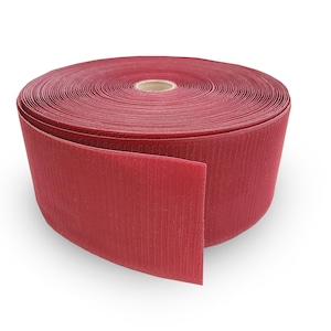 May include: A roll of red hook and loop tape, also known as Velcro. The tape is rolled up and a section is unrolled, showing the texture of the fabric.