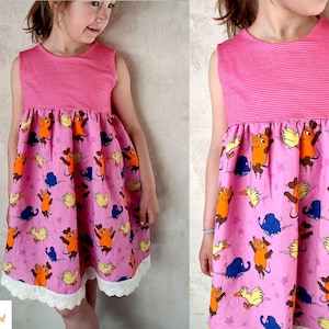 Könnte beinhalten: Ein pinkfarbenes, ärmelloses Kleid mit einem gestreiften Oberteil und einem Rock mit einem verspielten Druck von Comic-Tieren, Sternen und einem weißen Spitzenbesatz.