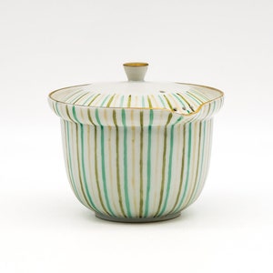 May include: White ceramic teapot with a lid, featuring green and gold stripes. The teapot has a small spout and a handle.