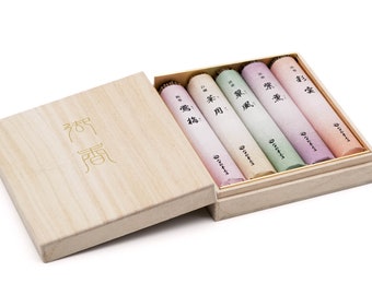 May include: A wooden box with a sliding lid, containing five different incense sticks. The box is labeled with the Japanese characters "香 薫". The incense sticks are wrapped in paper with different colors and Japanese characters.