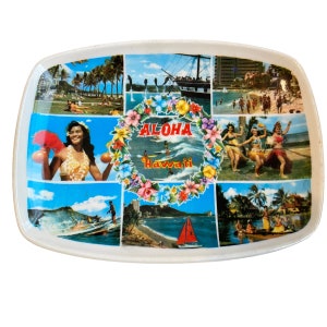 May include: Rectangular serving tray with a white border and a collage of Hawaiian scenes. The center features the word "Aloha" surrounded by flowers, with images of beaches, surfers, and dancers. The tray is a vintage souvenir.