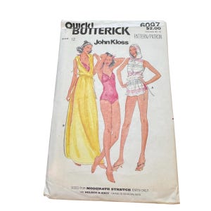 May include: A Butterick sewing pattern envelope, number 6097, size 12, by John Kloss. The front features illustrations of three outfits: a long yellow dress, a pink one-piece swimsuit, and a hooded top with shorts, all for moderate stretch knits.