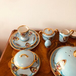 May include: A blue and gold tea set with floral designs. The set includes a teapot, creamer, sugar bowl, cup and saucer, and a covered dish.
