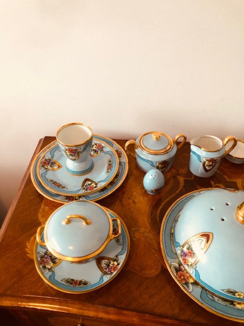 May include: A blue and gold tea set with floral designs. The set includes a teapot, creamer, sugar bowl, cup and saucer, and a covered dish.