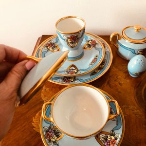 May include: A blue and gold tea set with floral designs. The set includes a teapot, sugar bowl, creamer, cup and saucer.