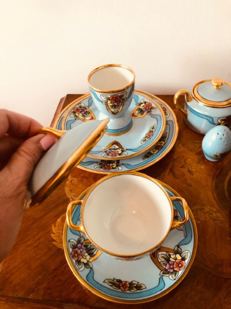 May include: A blue and gold tea set with floral designs. The set includes a teapot, sugar bowl, creamer, cup and saucer.