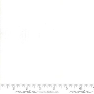 May include: A plain white fabric with a ruler at the bottom. The ruler is marked in inches and has the word "moda" printed on it.
