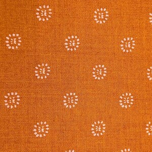 May include: Orange fabric with a white repeating pattern of small circles. The circles have a white outline and a white center with a small pink dot in the center.