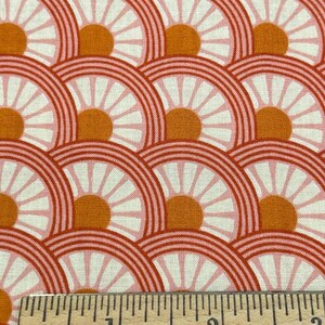 May include: A close-up of a fabric with a repeating pattern of pink and orange circles with white daisy-like designs. A ruler is placed at the bottom of the image with the text "WESTCOTT" and "MADE IN U.S.A." visible.