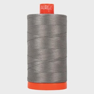 May include: A spool of Aurifil thread in a light gray color. The spool is wrapped in orange plastic.