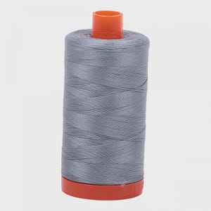 May include: A spool of gray thread with an orange plastic bobbin.