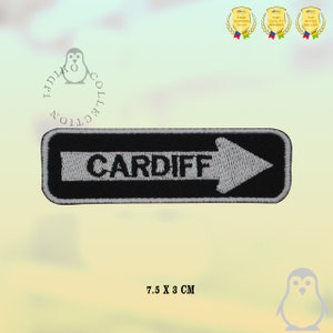 Peut inclure: Patch brodé noir et blanc avec le mot "CARDIFF" et une flèche blanche pointant vers la droite. Le patch mesure 7,5 cm sur 3 cm.