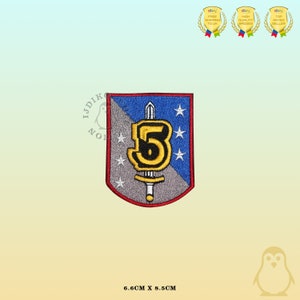 May include: A shield-shaped embroidered patch featuring a diagonal split of grey and blue. A central yellow number 5 is superimposed over a silver sword. Three white stars are on the blue side and two on the grey side. Dimensions are 6.6cm x 8.5cm.