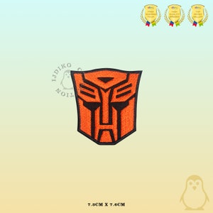 Peut inclure: Patch thermocollant brodé orange et noir représentant le logo des Transformers. Le logo est un visage de robot stylisé avec un fond noir et des détails orange. Le patch mesure 7,3 cm sur 7,6 cm.