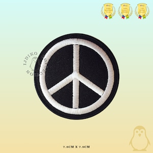 May include: A white peace sign embroidered on a black circular patch. The patch is 7.8 cm in diameter.